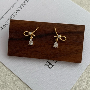 Golden knot bow stud earrings with teardrop crystal pendant on vintage display