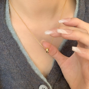 Detail of a minimalist gold cylinder pendant necklace with sparkling stars on a grey sweater