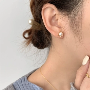 Elegant S925 silver pearl stud earrings with gold plating worn by model in soft lighting