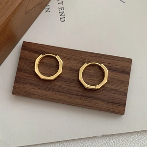 Détail de boucles d'oreilles dorées montrant les facettes octogonales et le fini poli