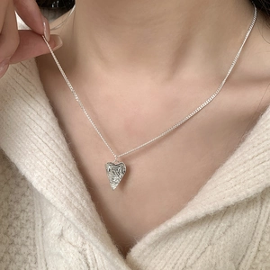Detailed view of an irregular heart pendant necklace on a model wearing a sweater