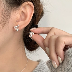Minimalist S925 sterling silver bow and heart earrings worn by a model for a sweet look