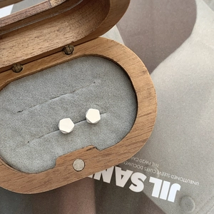 Minimalist geometric silver stud earrings showcased in a round wooden jewelry box