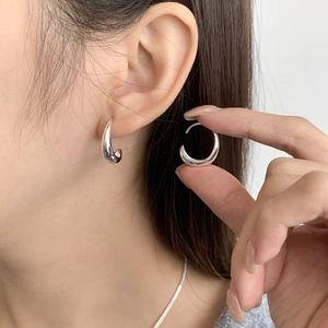 Primer plano de pendientes de aro minimalistas en plata S925 lucidos por una modelo