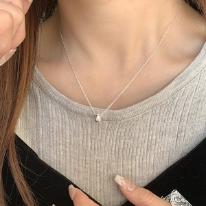 Close-up of minimalist S925 sterling silver chain with a polished ring pendant on a model
