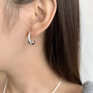 Primer plano de pendiente de media luna en plata S925 pulida en una modelo femenina
