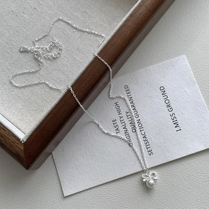 Detailed view of S925 sterling silver bow pendant with white pearl on a dainty chain