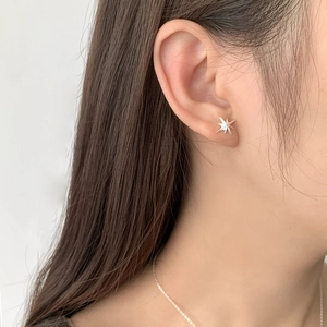 Close-up of a minimalist silver star stud earring worn on a model's earlobe