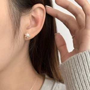 Macro shot of S925 sterling silver pearl stud earrings with gear-shaped beaded border