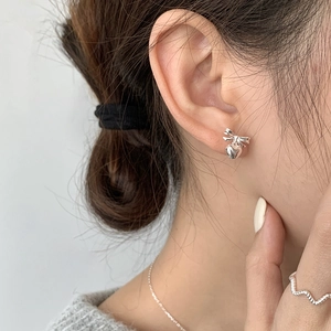 Close-up of ballet style silver bow heart earrings worn by a model with matching jewelry