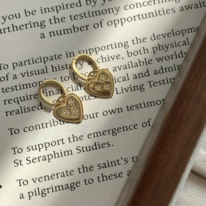 Macro view of gold heart earrings with starburst stone inlay and vintage beaded texture