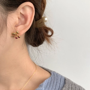Gros plan de boucles d'oreilles cerises en argent S925 doré portées par un mannequin