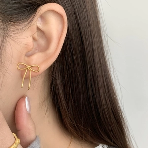 Gros plan de boucles d'oreilles nœud dorées avec texture torsadée et bague assortie