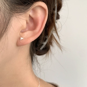 Close-up of minimalist S925 sterling silver triangle stud earring on a model ear