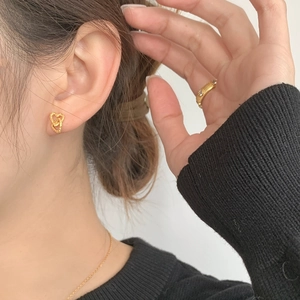 Close-up of golden S925 silver textured interlocking heart earrings on female model