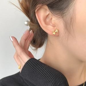 Vue rapprochée de boucles d'oreilles nœud doré portées pour un style élégant