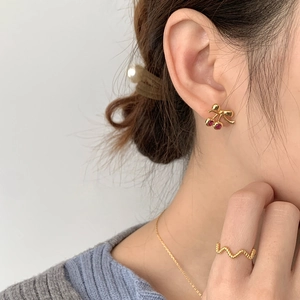Gros plan sur les boucles cerises en argent S925 et bague dorée portées par modèle