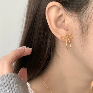 Boucles d'oreilles nœud dorées avec texture en spirale, portées par un mannequin