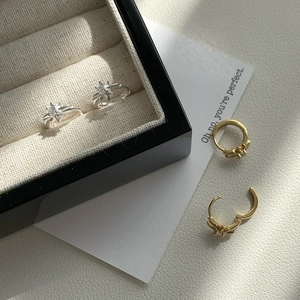 Dettaglio di orecchini a stella in argento S925 con zirconi su base in pelle
