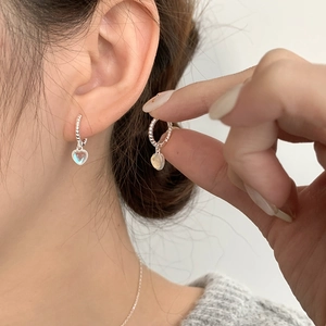 Close-up of S925 silver hoop earrings with heart moonstone charms on a model's ear