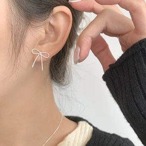 Boucles d'oreilles nœud élégantes en argent S925 portées avec texture ruban détaillée