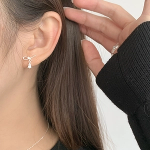 Detail of silver bow knot earring with clear water drop zircon on model's ear