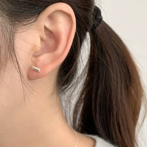 Close-up of minimalist rectangular S925 sterling silver stud earrings worn by model