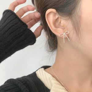Gros plan de boucles d'oreilles nœud en argent S925 avec texture portées par un mannequin