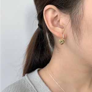 Detail of vintage gold heart earrings with star engraving and crystals on model