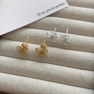Macro detail of S925 silver hollow lace bow stud earrings in gold and silver finishes