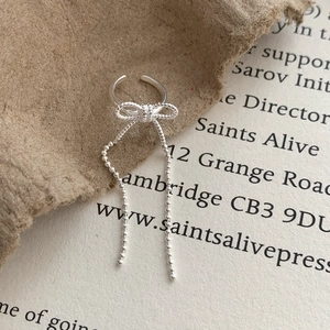 Detail of silver bow tassel earrings with delicate beaded chains and vintage aesthetic