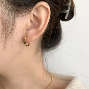 Créoles hexagonales dorées polies portées par un mannequin pour un look minimaliste chic