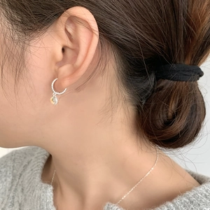 Close-up of S925 silver twist hoop earring with yellow gemstone on model