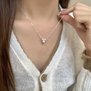Close-up of S925 sterling silver bow and heart pendant necklace on collarbone