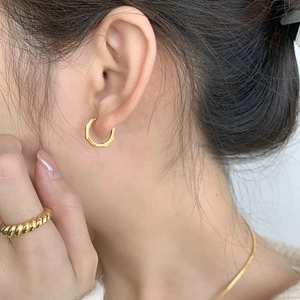 Détail d'un modèle portant des boucles d'oreilles hexagonales dorées géométriques