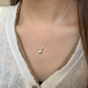 Elegant S925 sterling silver necklace featuring a bow and heart pendant on a model