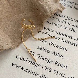 Elegant gold bow tassel ear cuff with beaded chain dangles in a vintage aesthetic setting