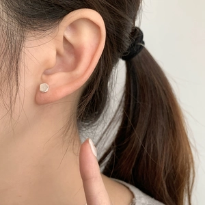 Close-up of minimalist S925 sterling silver hexagonal stud earring worn on the earlobe