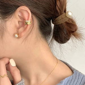 Detail of quilted gold ear cuff with small crystals and classic pearl stud earring