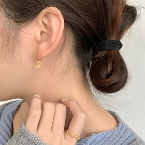 Detail showing gold twist hoop earrings with heart charms and a wavy textured ring