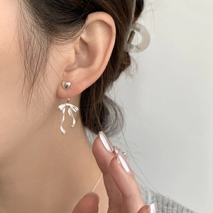 Close-up of S925 silver heart stud earrings with ribbon bow pendant worn by a model