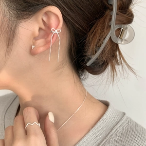 Detail of 925 sterling silver bow tassel ear cuff and wavy ring on female model