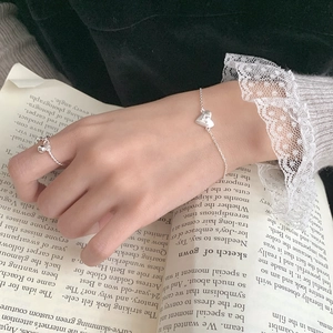 Detail of minimalist S925 silver heart bracelet and bead ring worn on hand