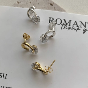 Macro detail of criss-cross U-shaped silver and gold stud earrings with brilliant cubic zirconia