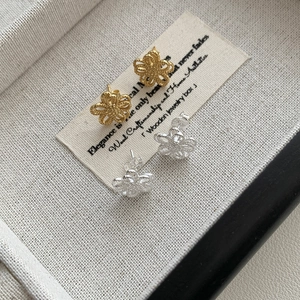 Detail of elegant hollow flower stud earrings in vintage gold and polished silver finish