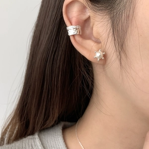 Close-up of stacked S925 silver ear cuffs with micro-pave crystals and a pearl stud