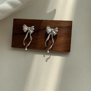 Boucles d'oreilles nœud argentées avec fini métallique sur présentoir en bois