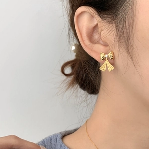Boucles d'oreilles nœud doré et feuille de ginkgo avec perle blanche sur un mannequin