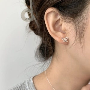 Close-up of S925 sterling silver bow earrings with sparkling cubic zirconia on model