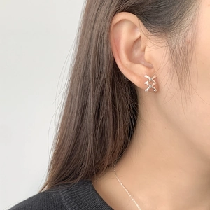 Close-up of elegant S925 sterling silver criss-cross stud earring worn on model